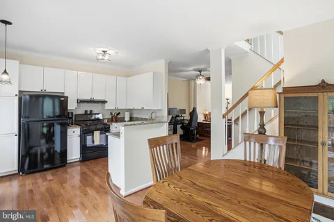 a kitchen with granite countertop a refrigerator oven a sink a stove and white cabinets with wooden floor