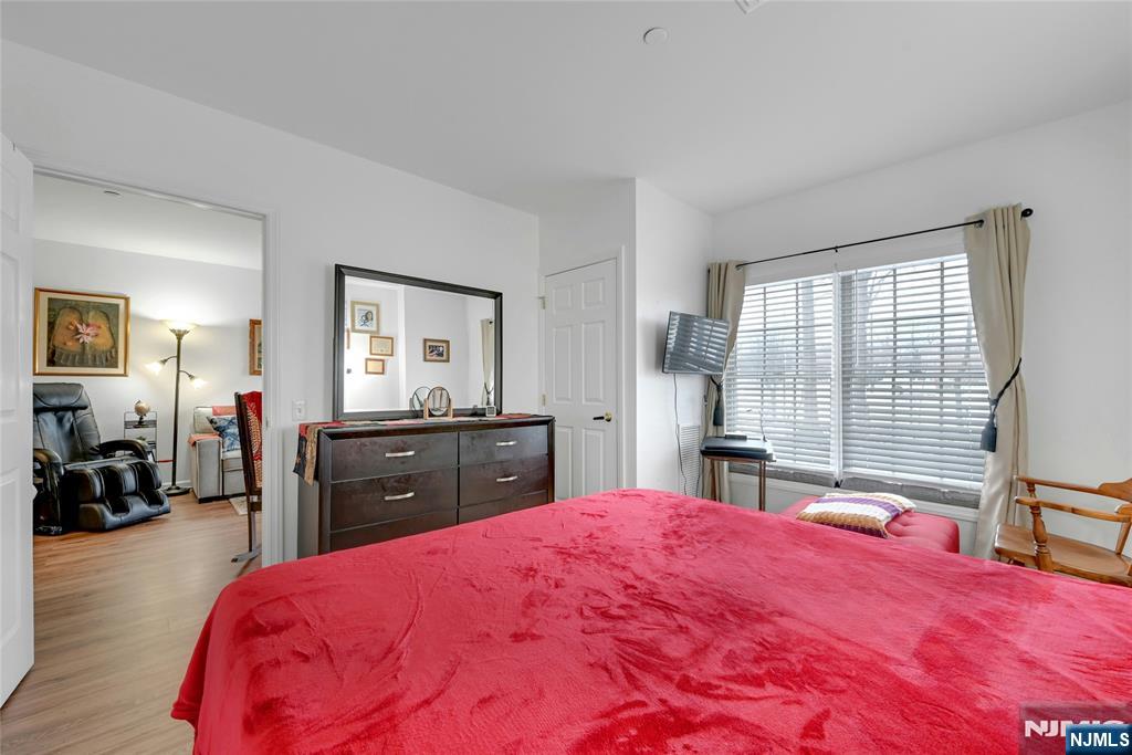 189 Forest Avenue, Unit 117 Paramus, NJ 07652 - Photo 10 of 15 a bedroom with a bed and a large window with mirror