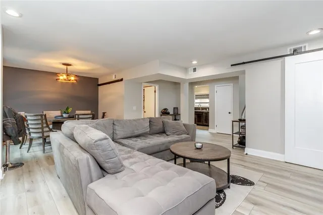 a living room with furniture and a dining table with wooden floor