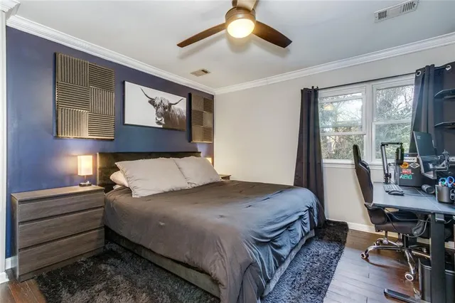 a bedroom with a bed a desk and chair with a large mirror next to a window