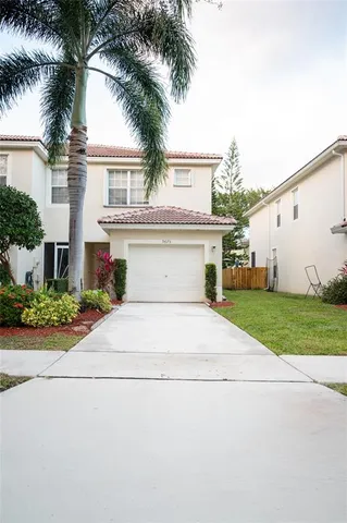 front view of house with a yard and palm trees