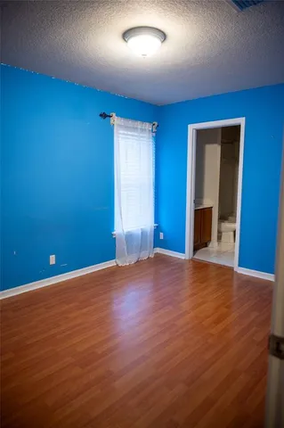 a view of an empty room with wooden floor and closet