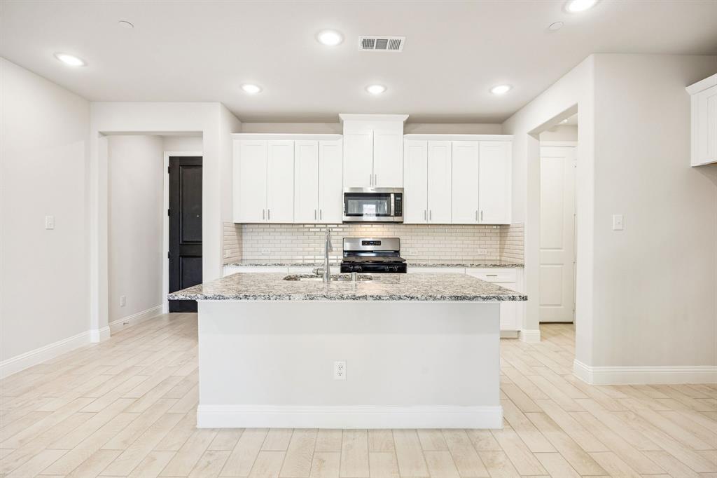 a kitchen with stainless steel appliances granite countertop a stove a sink and a refrigerator