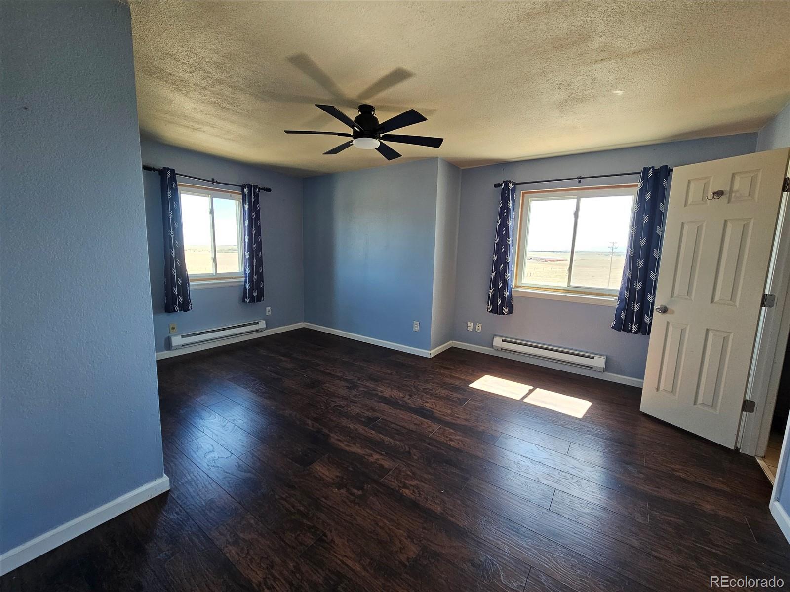 16985 Sage Crest Road Peyton, CO 80831 - Photo 16 of 25 an empty room with wooden floor and windows