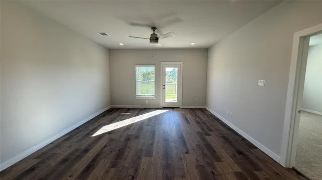 a view of an empty room with wooden floor and a window