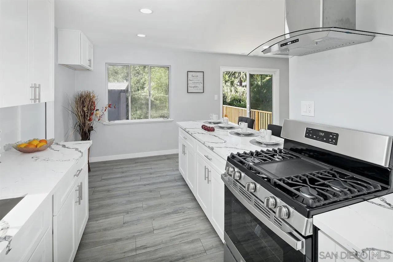 1050 Tiger Tail Road Vista, CA 92084 - Photo 7 of 28 a kitchen with a stove a sink a window and wooden floor