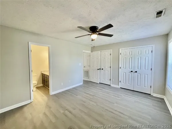 a view of empty room with wooden floor and ceiling fan