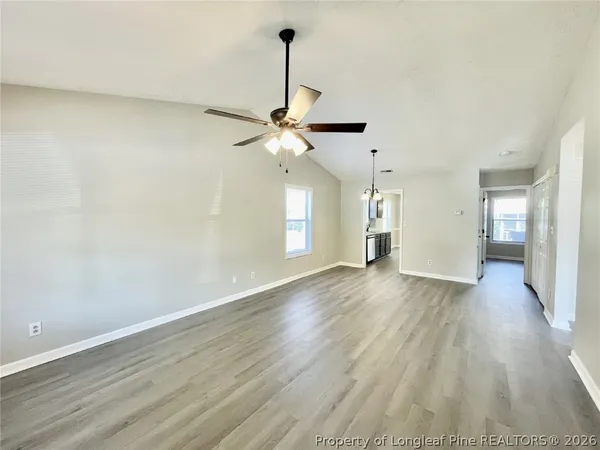 a view of an empty room with window and wooden floor