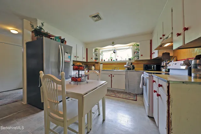 a kitchen with stainless steel appliances granite countertop a refrigerator a sink dishwasher a dining table and chairs with wooden floor