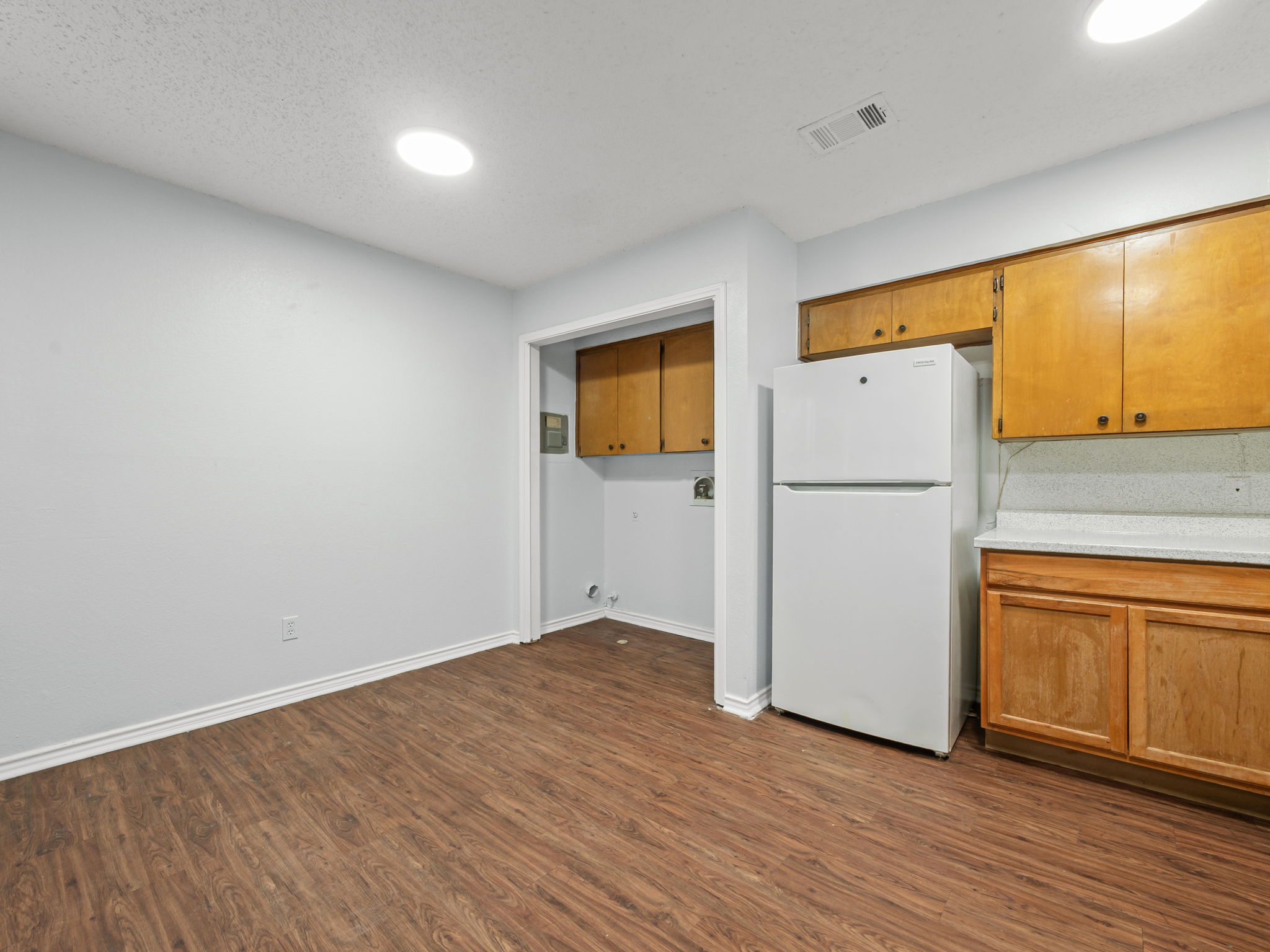 1816 Rawhide Loop, Unit 1822 Round Rock, TX 78681 - Photo 5 of 17 Kitchen with freestanding refrigerator, dark wood finished floors, light countertops, and brown cabinets