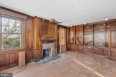 a view of an empty room with a fireplace and a window