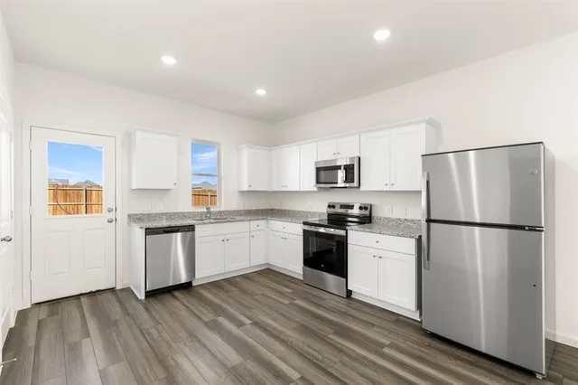 a kitchen with a refrigerator a stove top oven and white cabinets