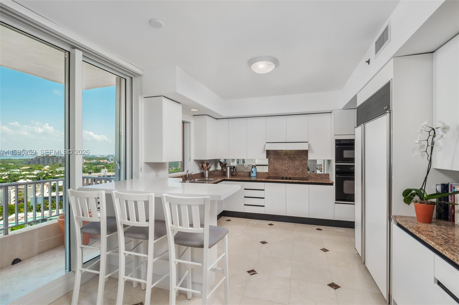 781 Crandon Boulevard, Unit 1603 Key Biscayne, FL 33149 - Photo 8 of 34 a large kitchen with granite countertop a large window and stainless steel appliances