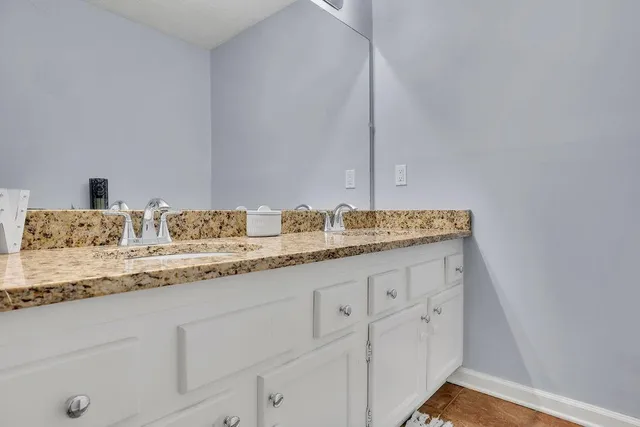 a bathroom with a granite countertop toilet sink and mirror