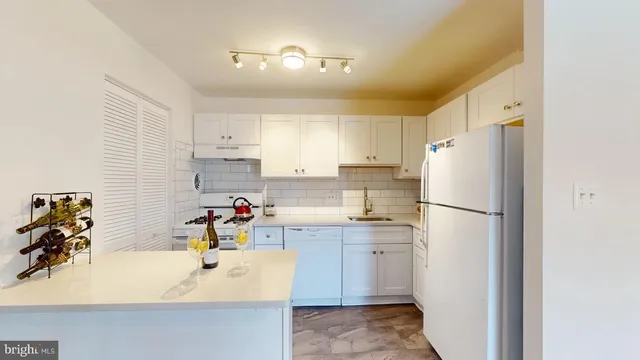a kitchen with a refrigerator a sink a stove and white cabinets