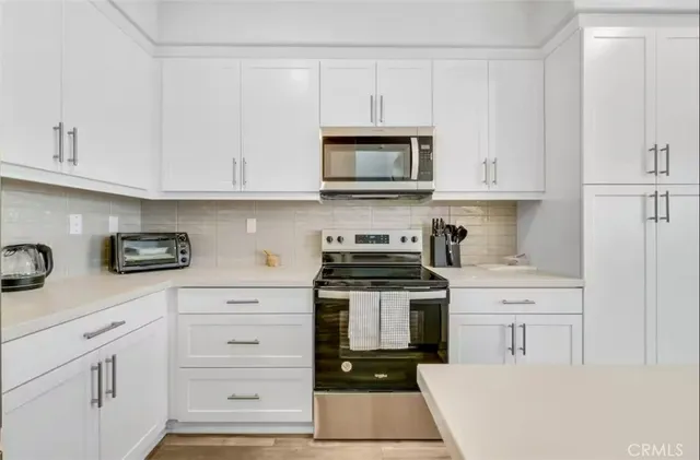 a kitchen with white cabinets and appliances