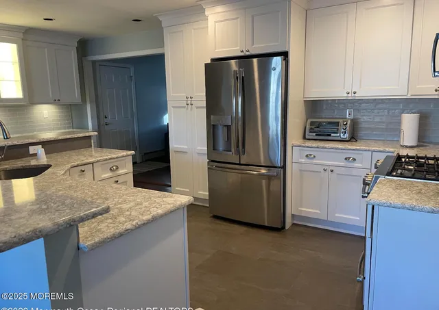 a kitchen with granite countertop a refrigerator stove and sink