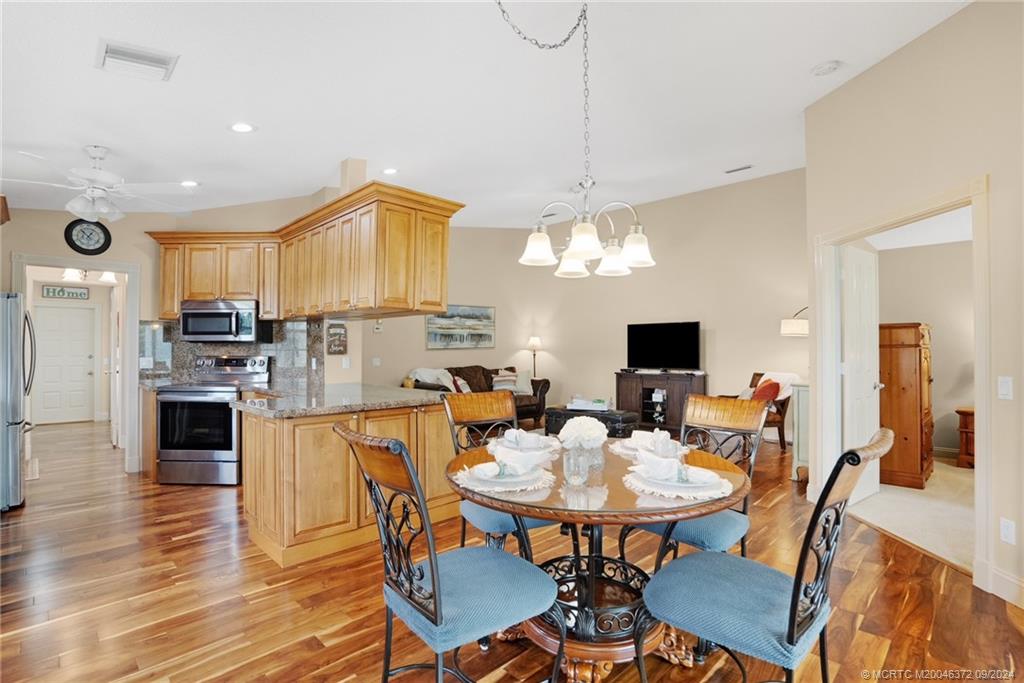 1663 Southwest Springfield Court Palm City, FL 34990 - Photo 7 of 27 a view of a dining room with furniture a chandelier and wooden floor