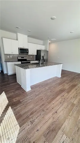 a kitchen with stainless steel appliances wooden floors and view living room