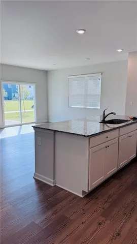 a kitchen with granite countertop wooden floors and white cabinets