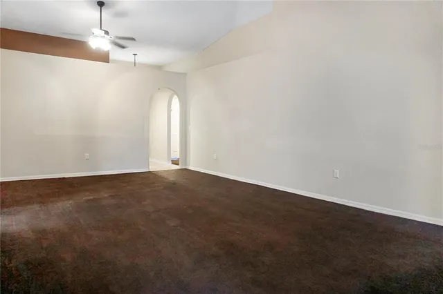 an empty room with a chandelier fan and windows