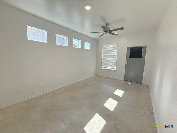 an empty room with a windows and ceiling fan