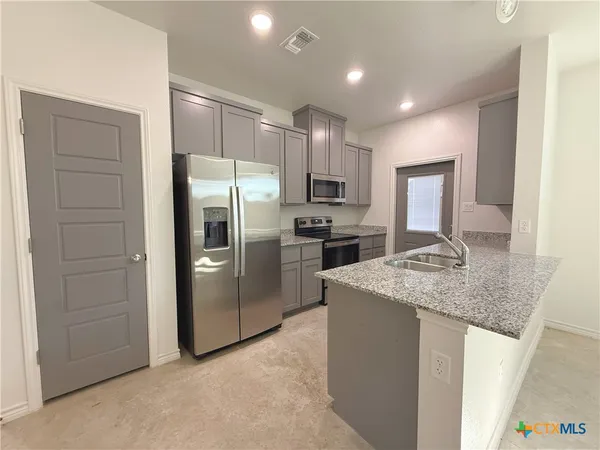 a kitchen with kitchen island a counter top space cabinets stainless steel appliances and a counter space