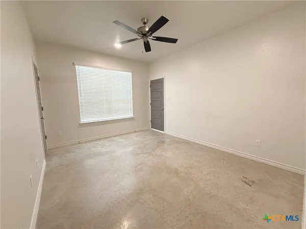 an empty room with a ceiling fan and window