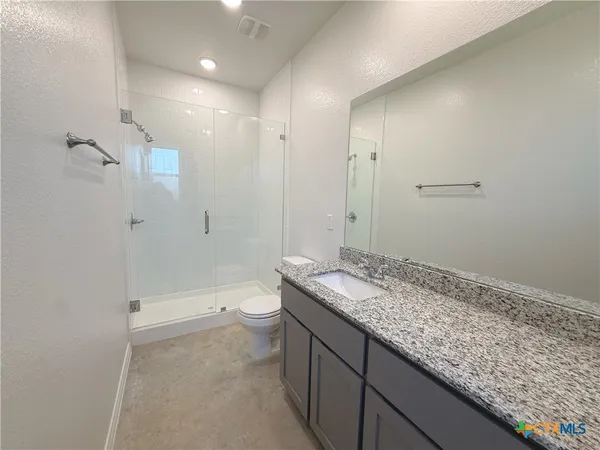 a bathroom with a granite countertop sink a toilet and shower