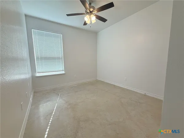 an empty room with a window and a fan