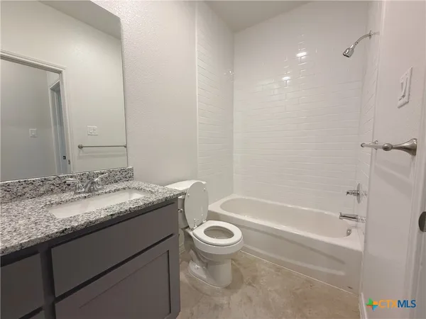 a bathroom with a granite countertop sink a toilet and bathtub