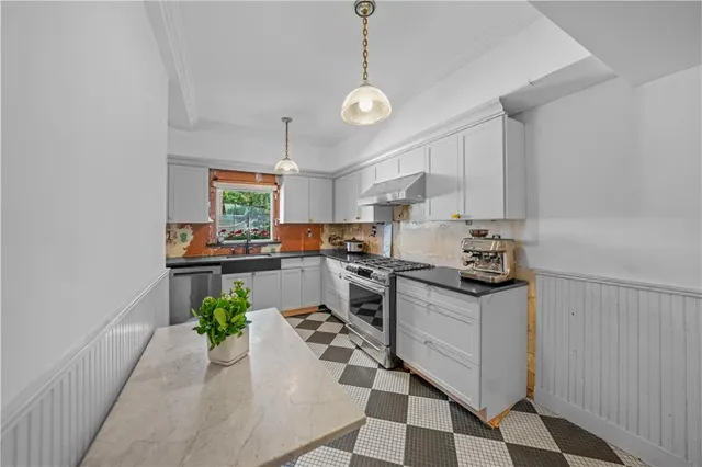 a kitchen with stainless steel appliances granite countertop a refrigerator a sink dishwasher a stove a dining table and chairs with wooden floor