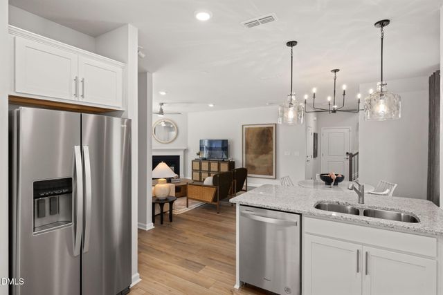 a kitchen with stainless steel appliances granite countertop a refrigerator a sink and white cabinets