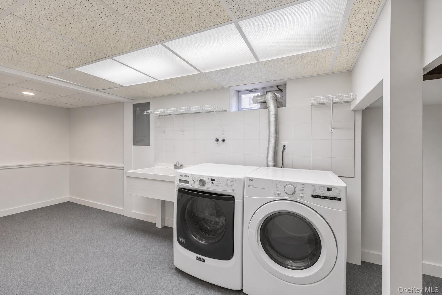 60 Croyden Road Mineola, NY 11501 - Photo 28 of 33 Dedicated laundry area featuring a utility sink, white tiled backsplash, and overhead wire shelving