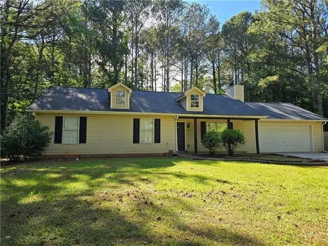 a front view of house with yard and trees in the background