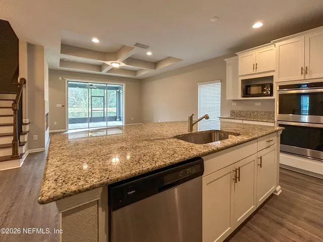 a kitchen with granite countertop sink stove and cabinets