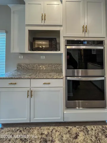 a kitchen with granite countertop white cabinets and oven