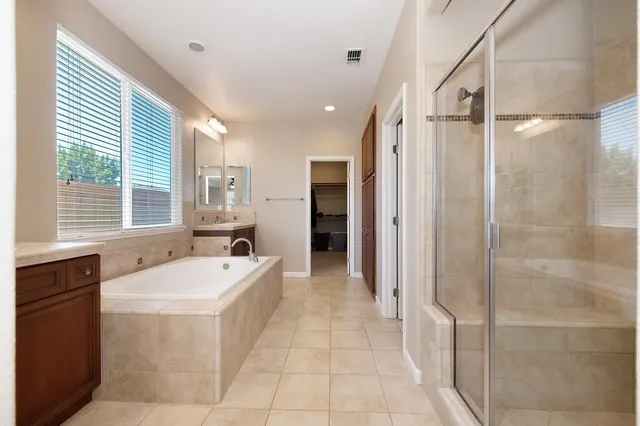 a spacious bathroom with a tub sink and mirror