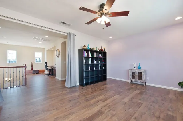 a view of a livingroom with a workspace wooden floor and a ceiling fan