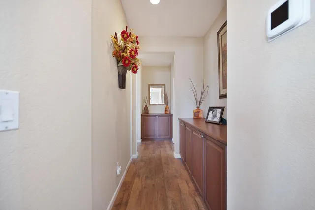 a view of a hallway to a livingroom with wooden floor and furniture