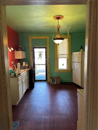 a kitchen with stainless steel appliances kitchen island granite countertop a refrigerator a stove and a wooden floors