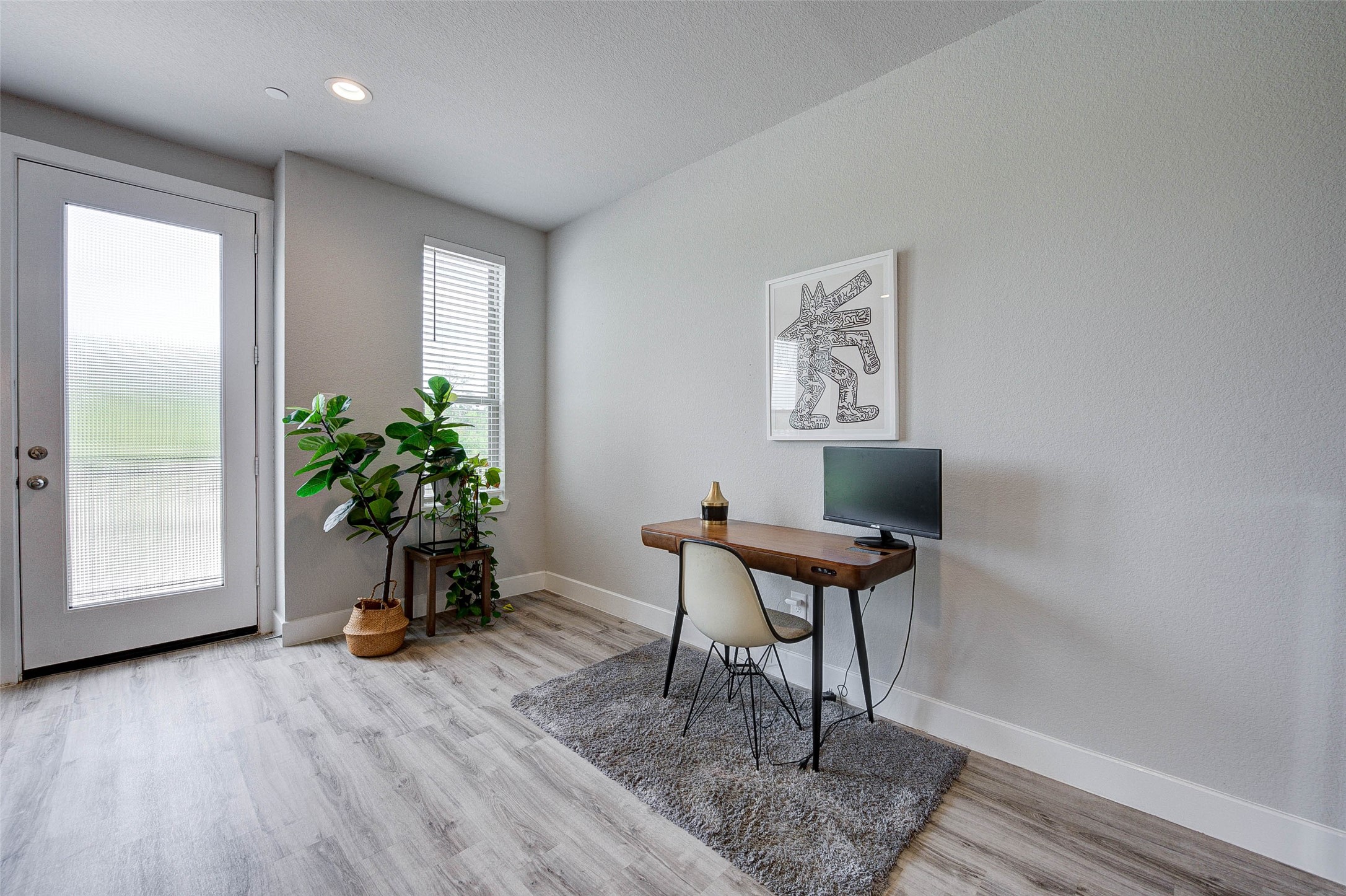 18732 Centro Main Street, Unit B Shenandoah, TX 77385 - Photo 17 of 42 Bright and modern home office with light wood flooring, a sleek desk, and a stylish chair. Large windows and a glass door provide ample natural light, while indoor plants add a touch of greenery. Perfect for a productive work environment.