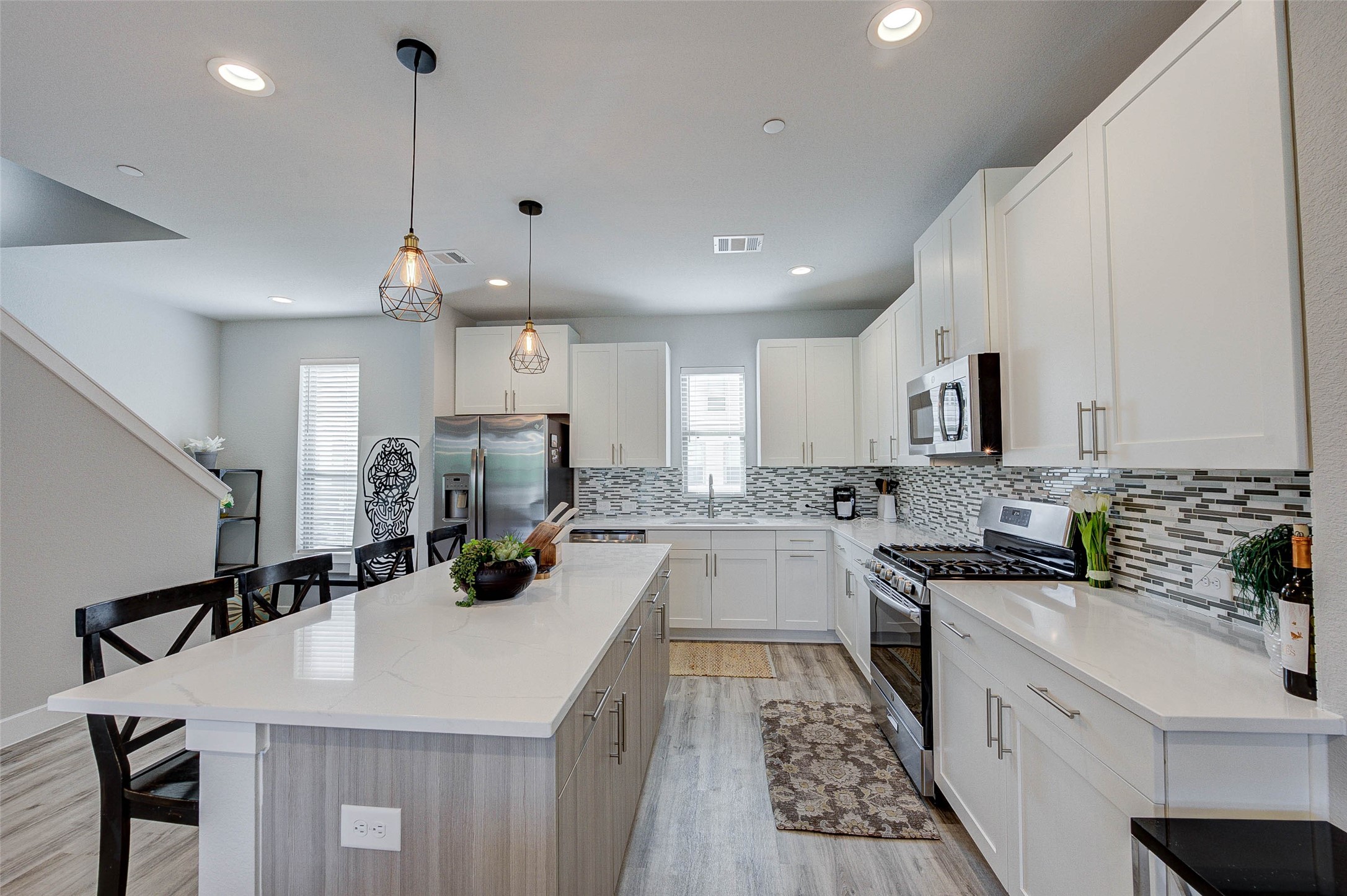 18732 Centro Main Street, Unit B Shenandoah, TX 77385 - Photo 20 of 42 This modern kitchen features sleek white cabinetry, stainless steel appliances, and a stylish tile backsplash. The spacious island offers additional seating and workspace, while pendant lighting adds a warm touch. Natural light fills the room, highlighting the open layout and contemporary design.