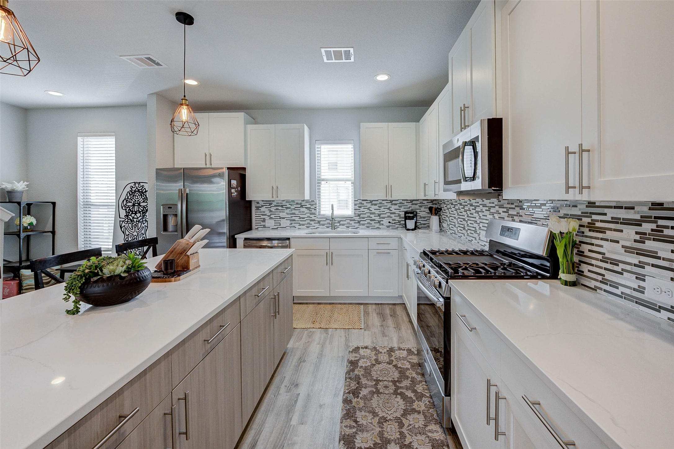 18732 Centro Main Street, Unit B Shenandoah, TX 77385 - Photo 21 of 42 This modern kitchen features sleek white cabinetry, a stylish tile backsplash, and stainless steel appliances. It includes a spacious island with ample counter space and elegant pendant lighting, perfect for entertaining.