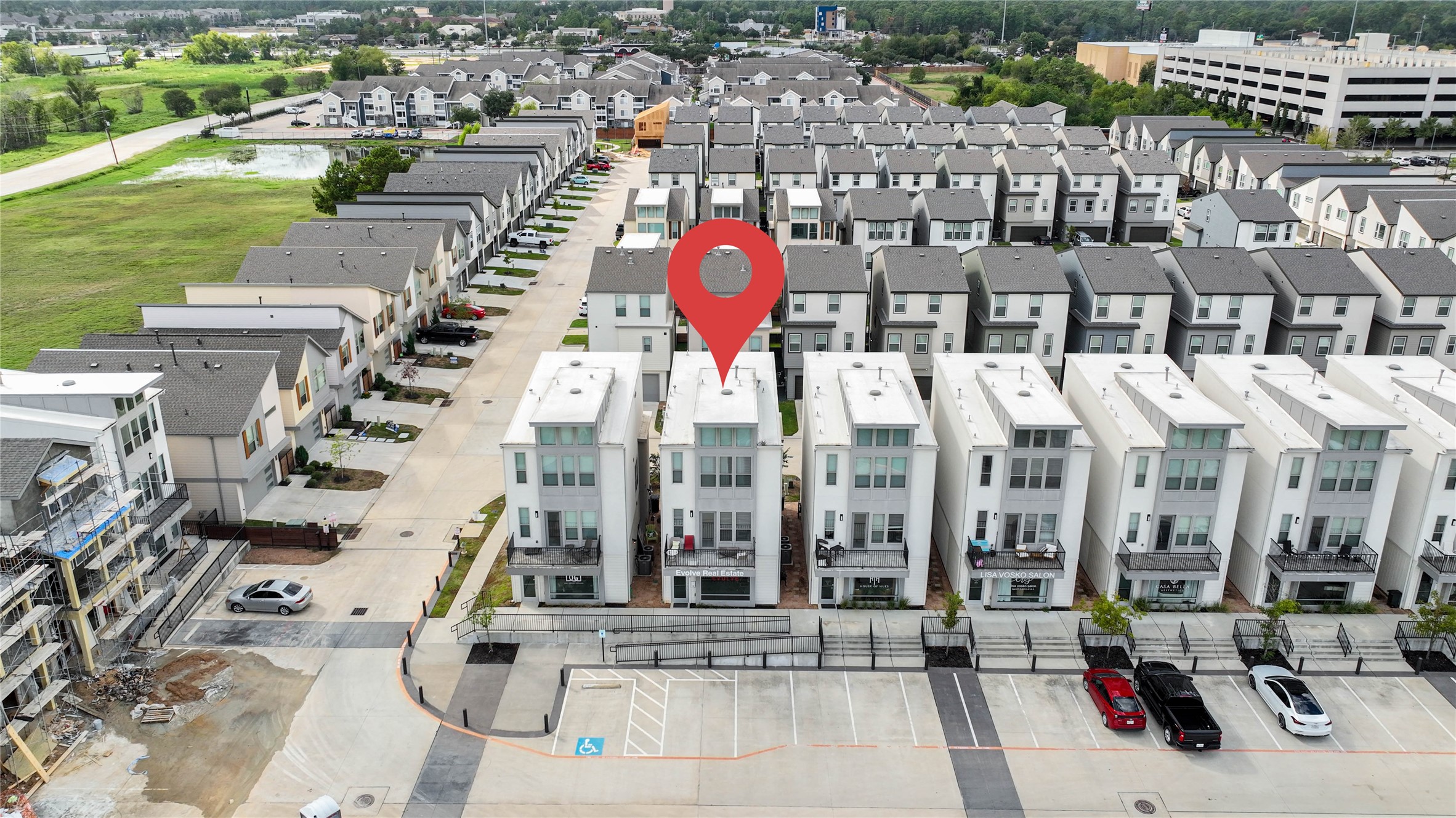 18732 Centro Main Street, Unit B Shenandoah, TX 77385 - Photo 41 of 42 Modern row of white townhouses with clean lines and multiple stories, located in a well-organized residential community. The area appears spacious with parking and green surroundings, providing a suburban feel close to urban amenities.