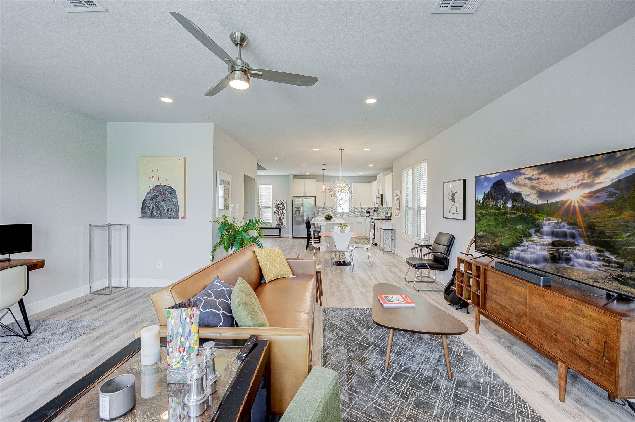 18732 Centro Main Street, Unit B Shenandoah, TX 77385 - Photo 7 of 42 Spacious open-concept living area with modern design, featuring a cozy seating area, stylish decor, and a large TV. The room flows into a bright kitchen and dining space, highlighted by sleek appliances and contemporary lighting. Ideal for entertaining and family gatherings.