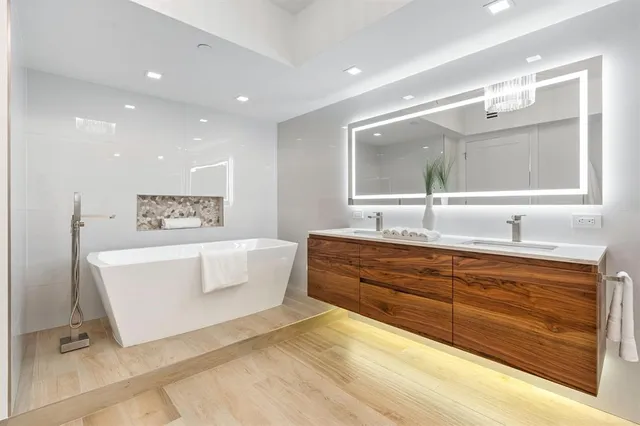 a spacious bathroom with a double vanity sink large mirror and bathtub