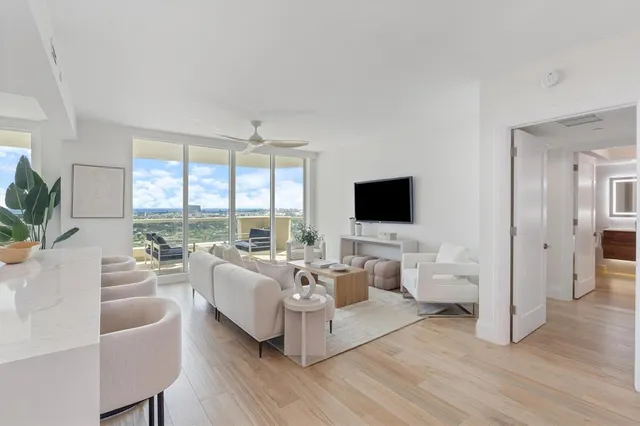 a living room with furniture flat screen tv and a large window