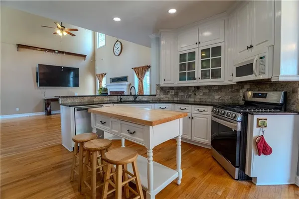 a kitchen with stainless steel appliances granite countertop a stove a sink and a microwave