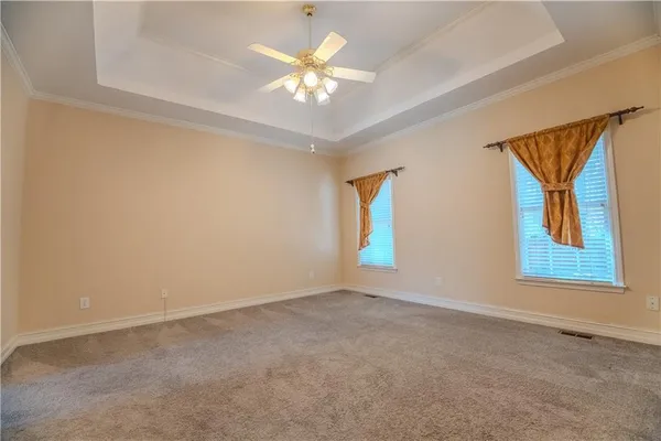 an empty room with windows and chandelier fan